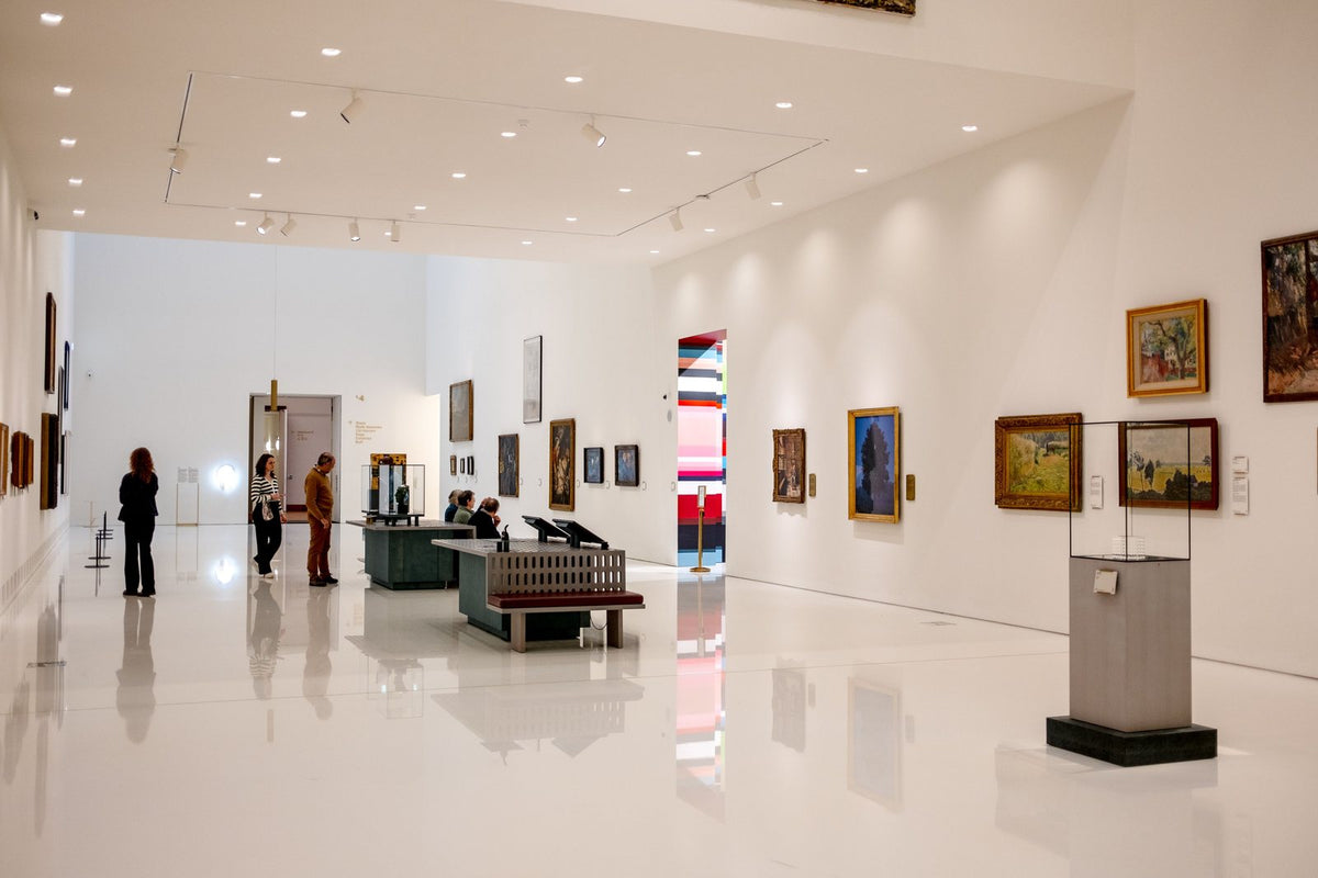 Beyaz duvarlı çağdaş sanat müzesinde eserleri inceleyen ziyaretçiler