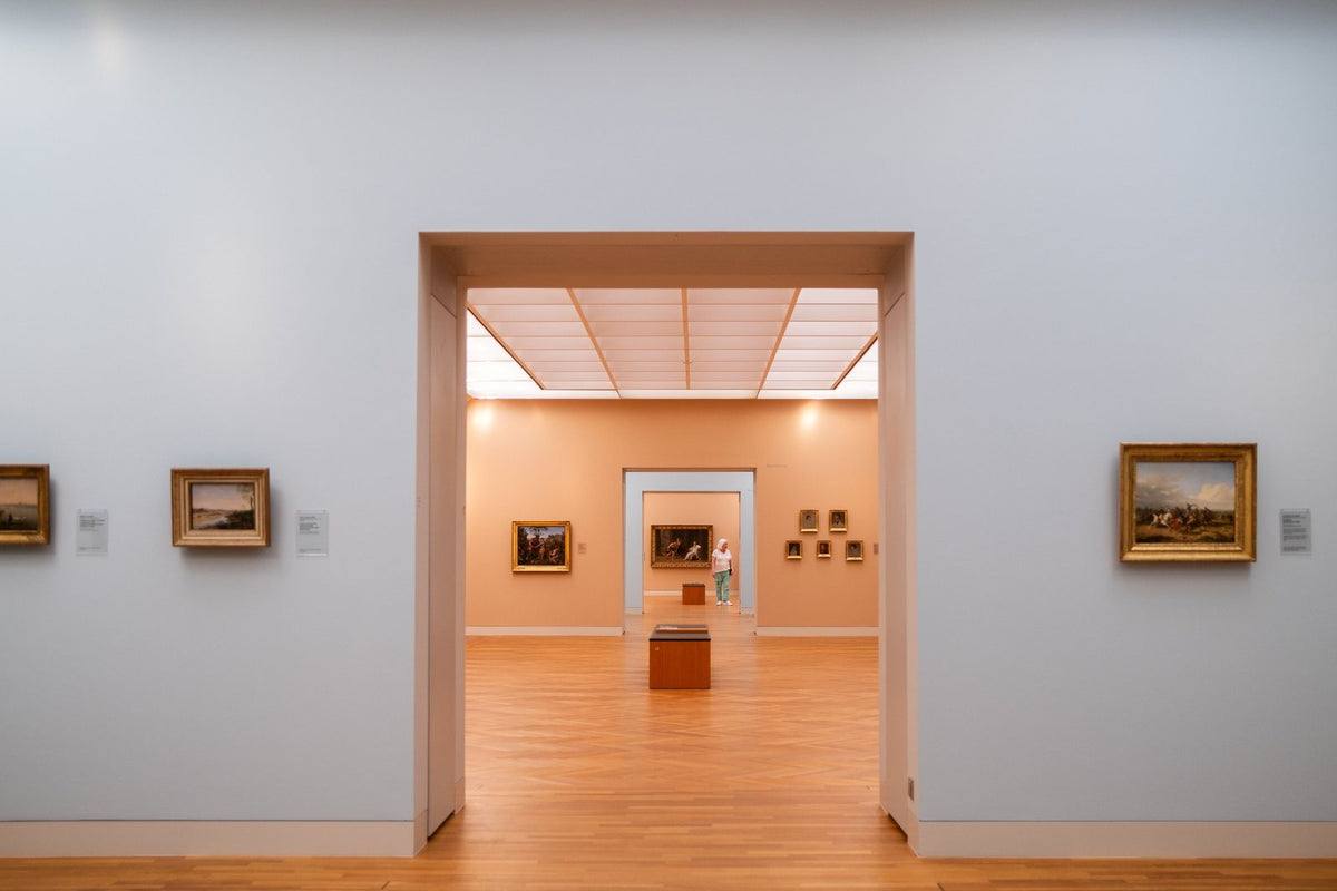 Müze salonunda art arda açılan beyaz kapılar ve çerçeveli eserler