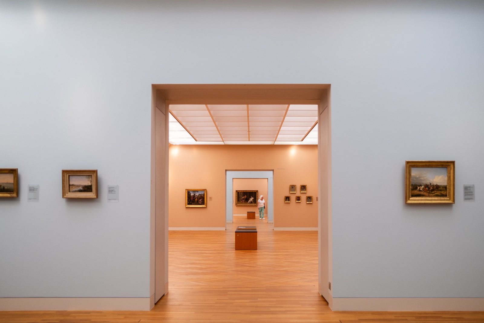 Müze salonunda art arda açılan beyaz kapılar ve çerçeveli eserler